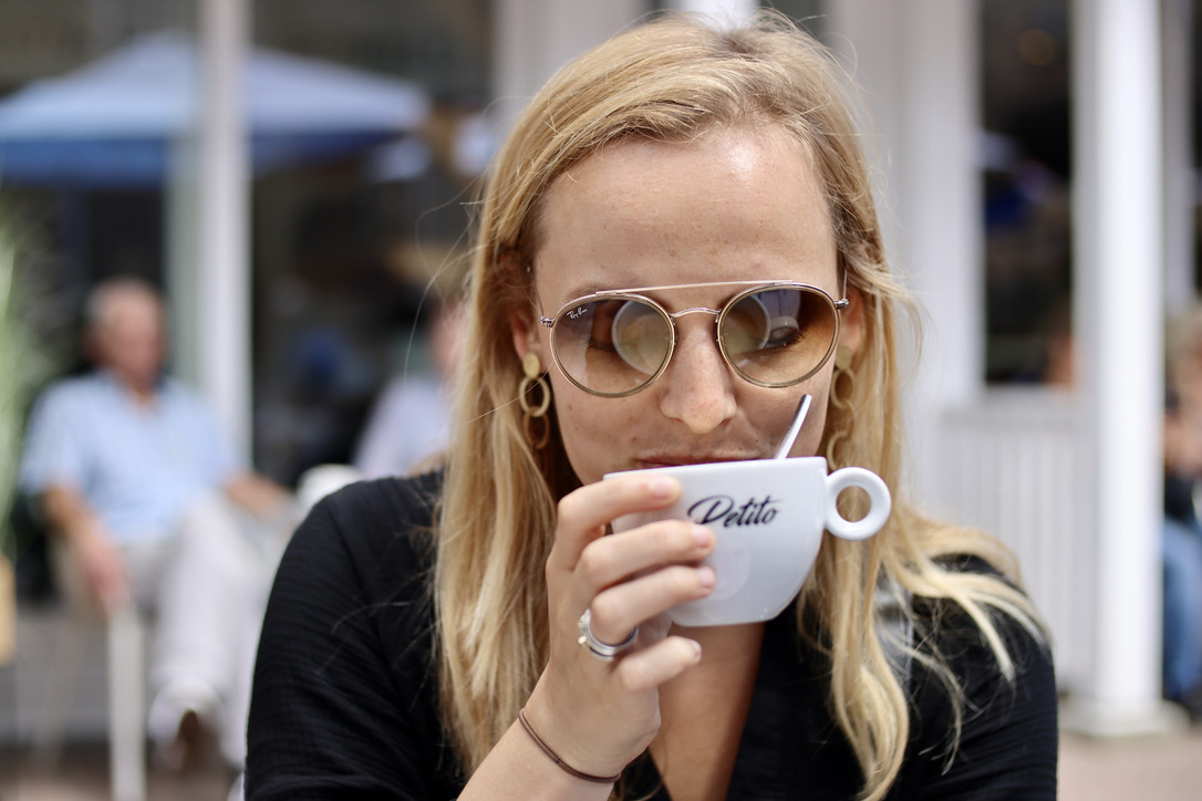 A customer drinking coffee out of a cup that has the Petito logo on it